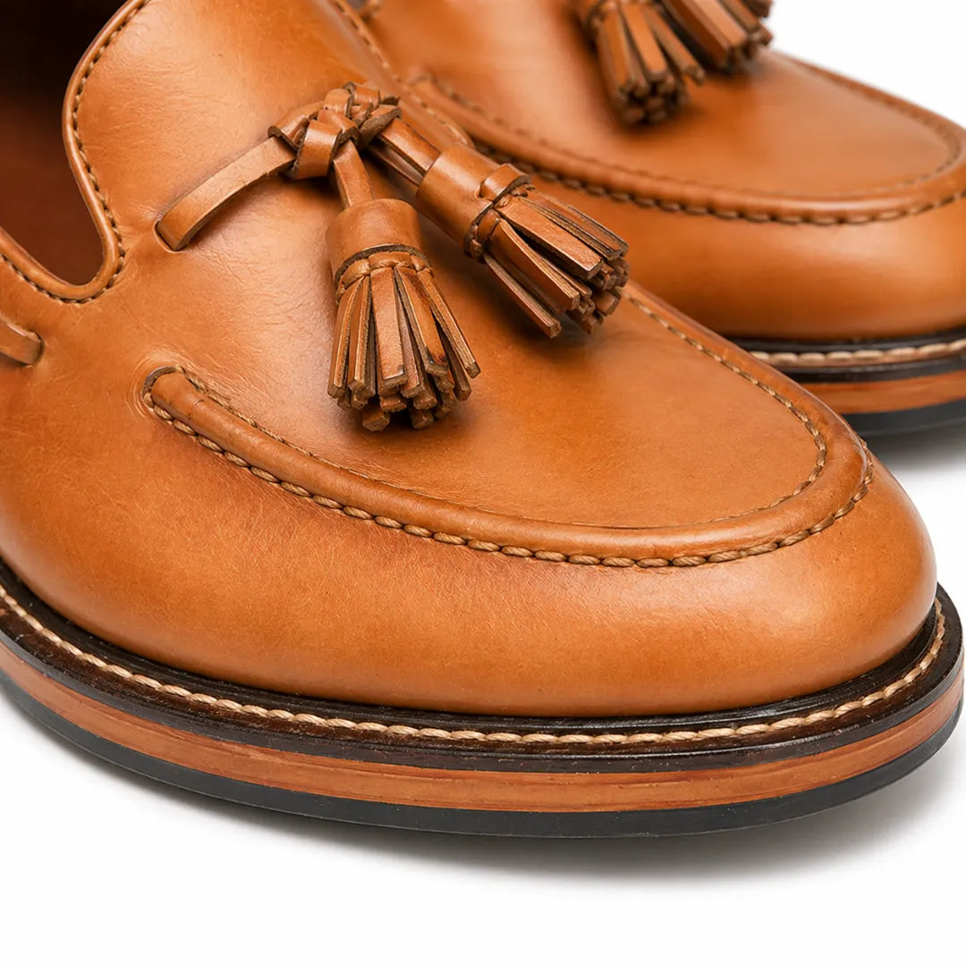 Close-up of brown leather loafers with tassels on a white background
#color_tan