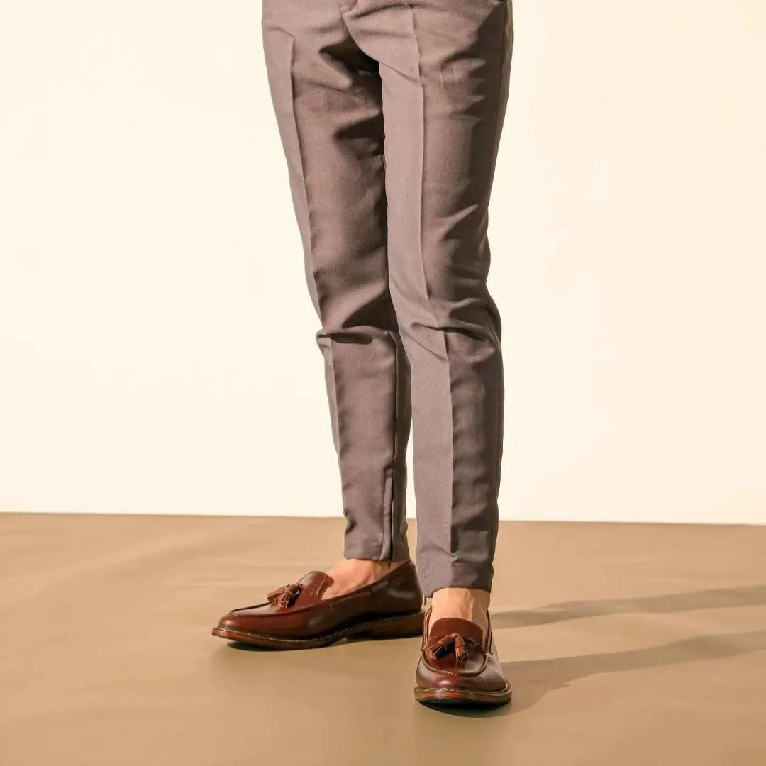 Person wearing Walnut brown tassel dress shoes and gray pants on a beige background
#color_walnut