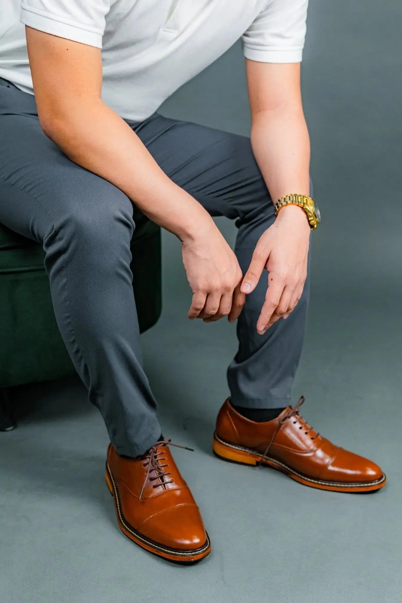Person wearing tan brown leather shoes and gray pants against a gray background
#color_tan