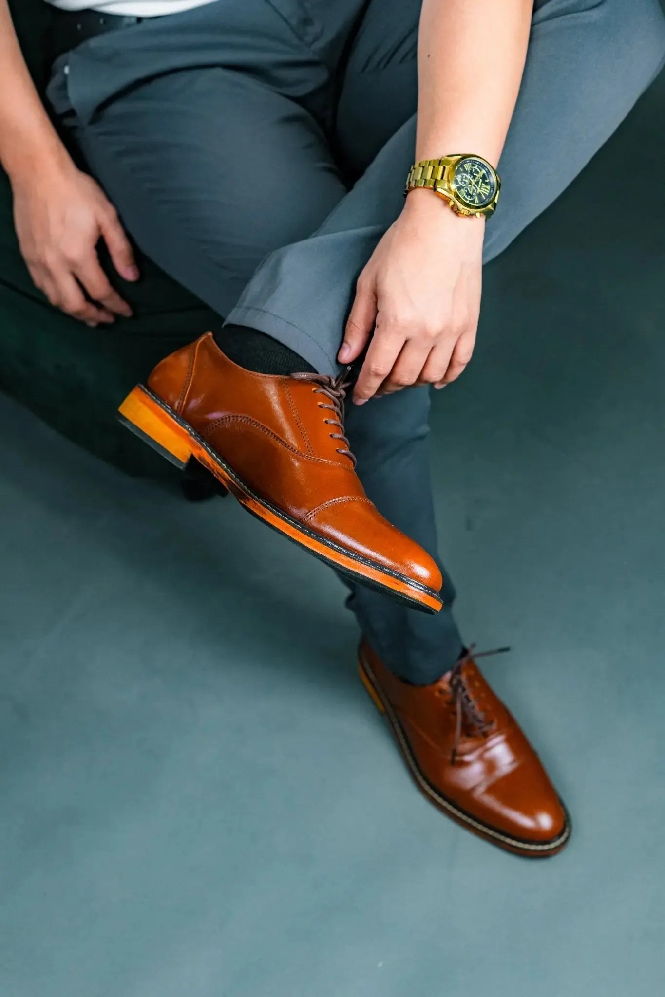 Person wearing brown dress shoes and gray pants on a gray floor.
#color_tan