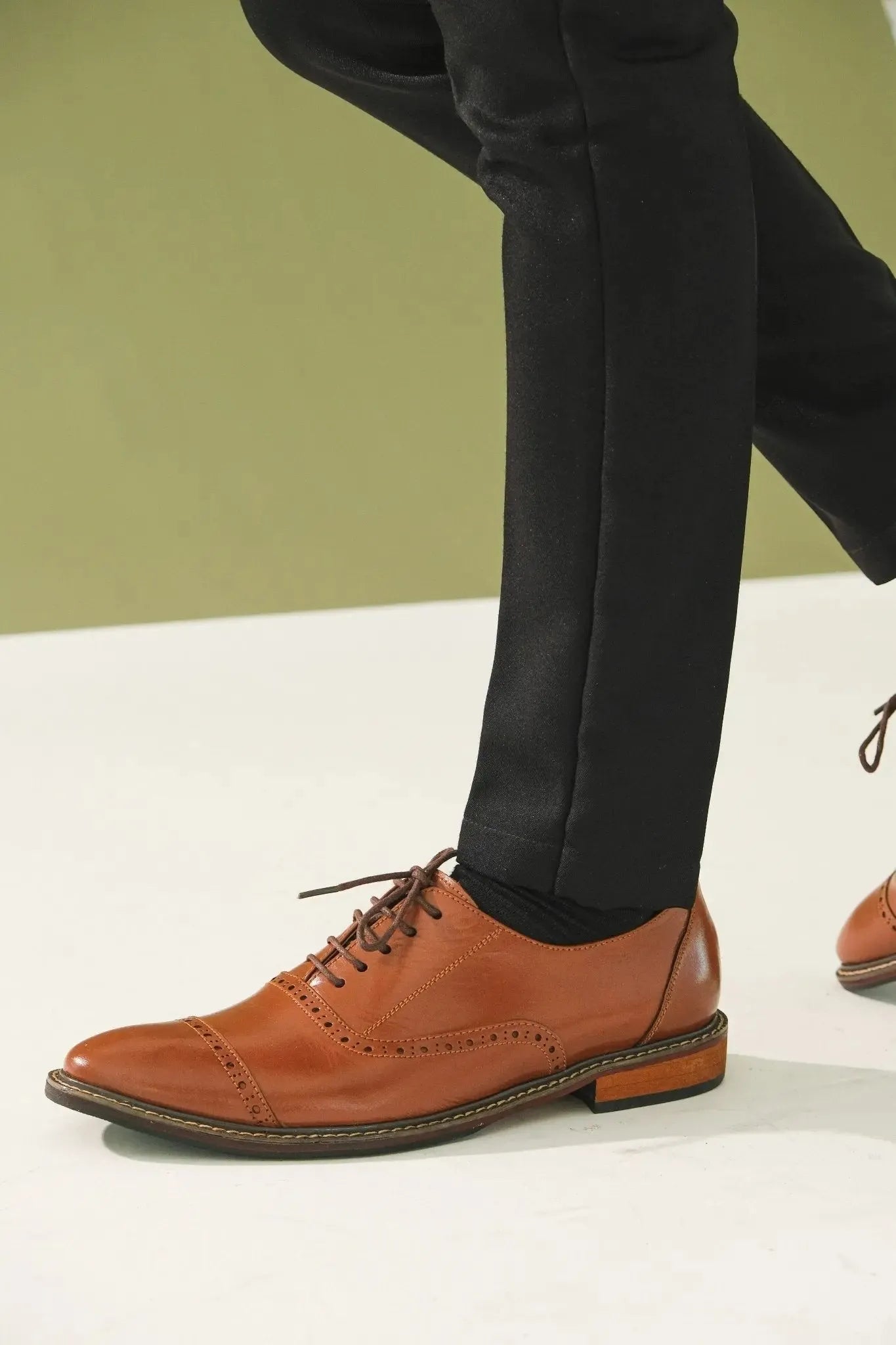 Oxford tan brown leather shoes worn with black pants on a neutral background
#color_tan