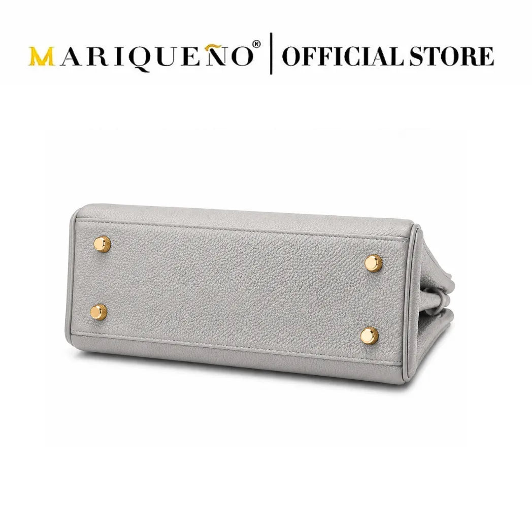 A light gray textured leather clutch or wallet-style handbag shown from the bottom corner, featuring four gold-tone metal studs on the front. The image has a white background with 'MARIQUEÑO | OFFICIAL STORE' text at the top.
#color_gray