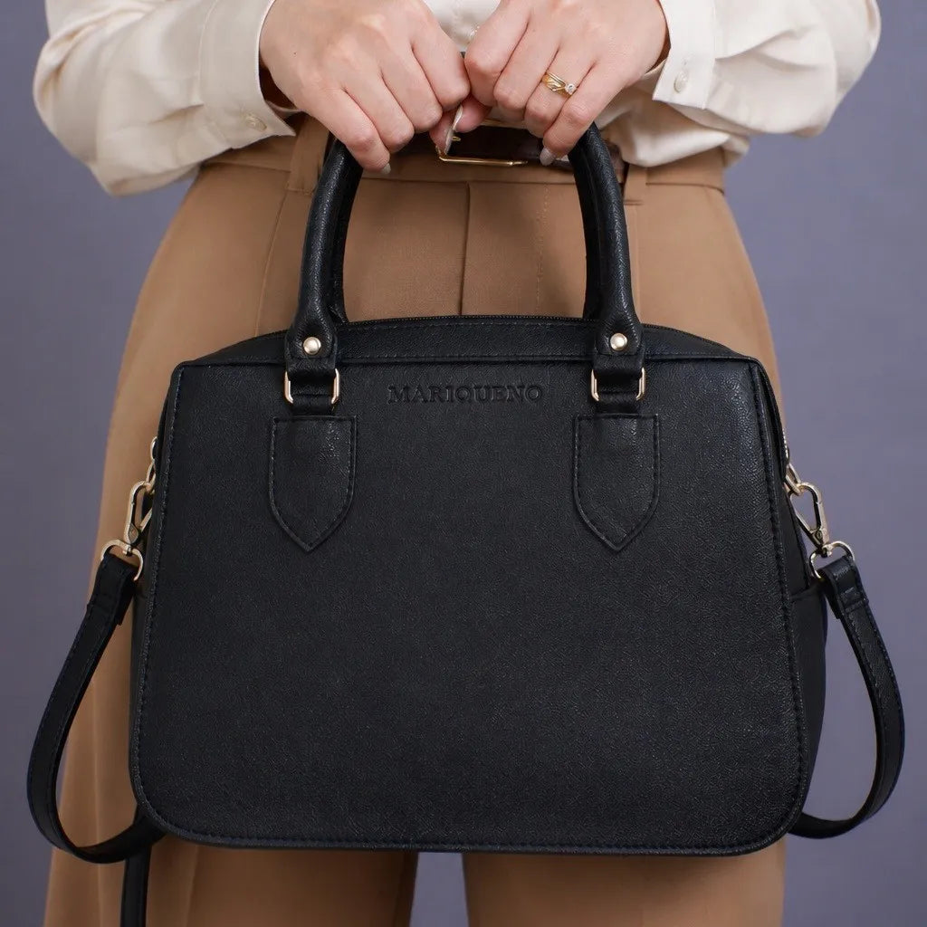 Black handbag with a visible brand logo held by a person against a plain background
#color_black