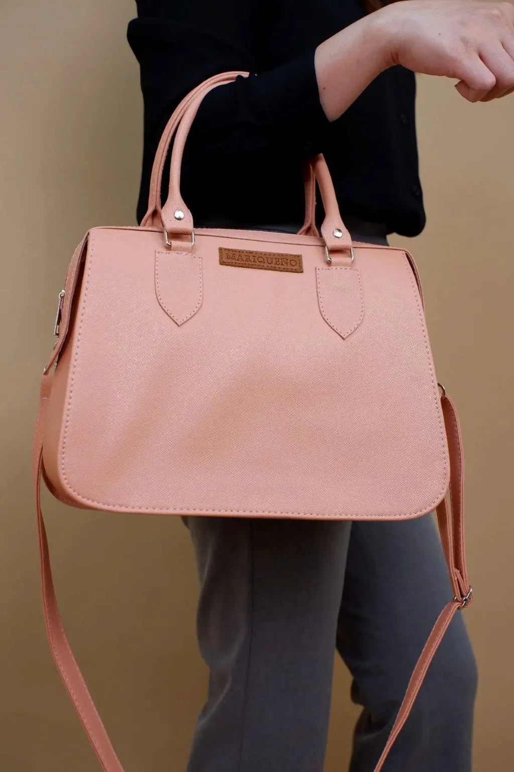 Person holding a pink handbag against a beige background
#color_salmon pink