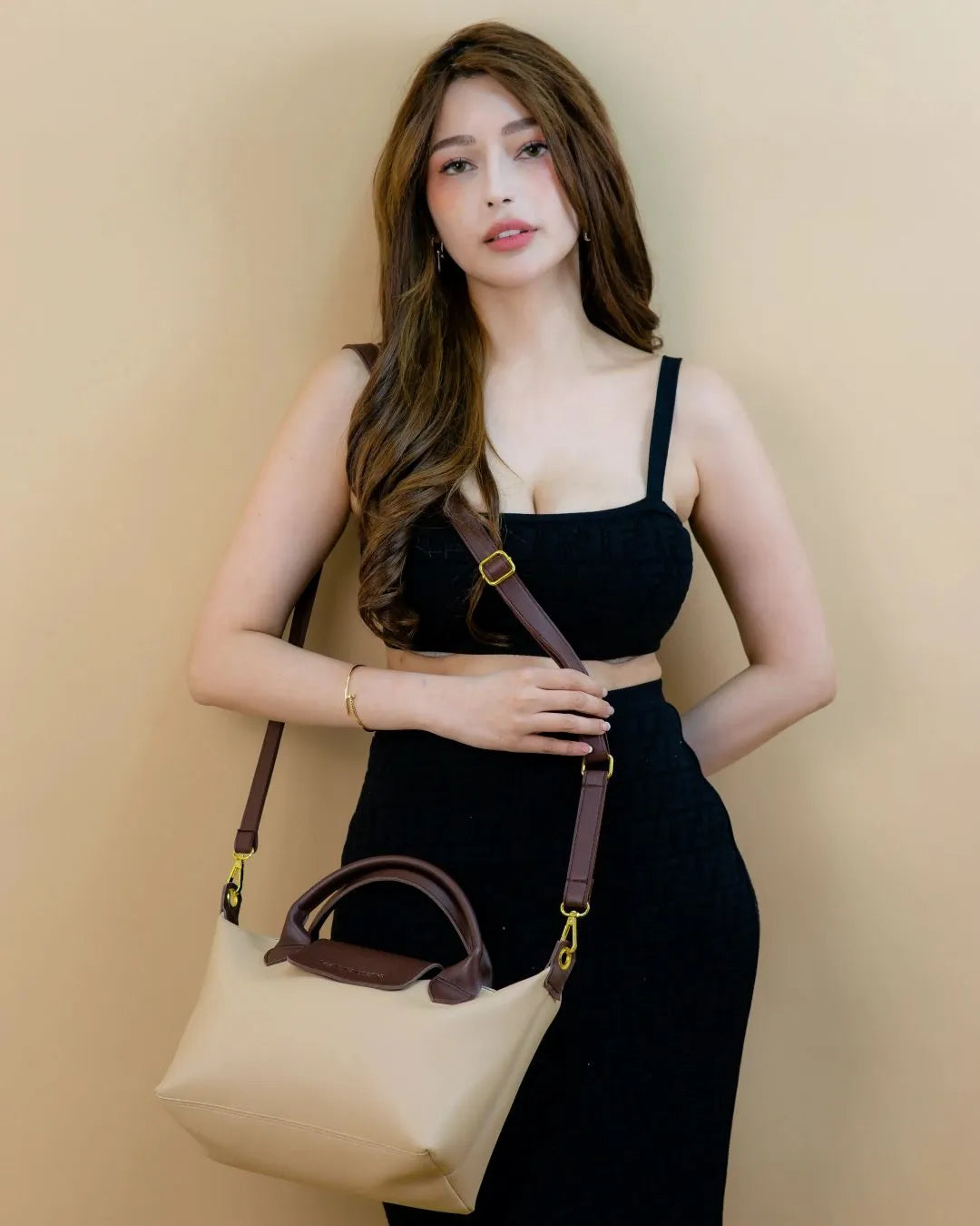 Woman holding a beige handbag against a beige background
#color_cream