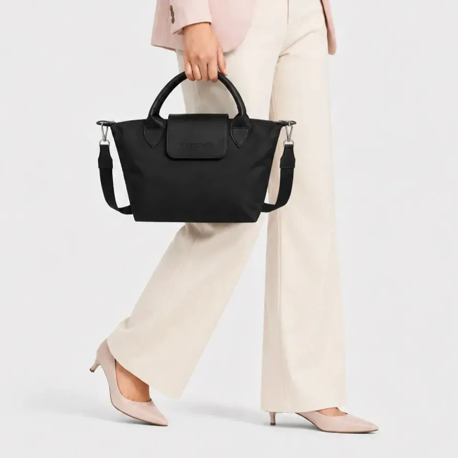 Person wearing a brown coat holding a black handbag on a white background
#color_black