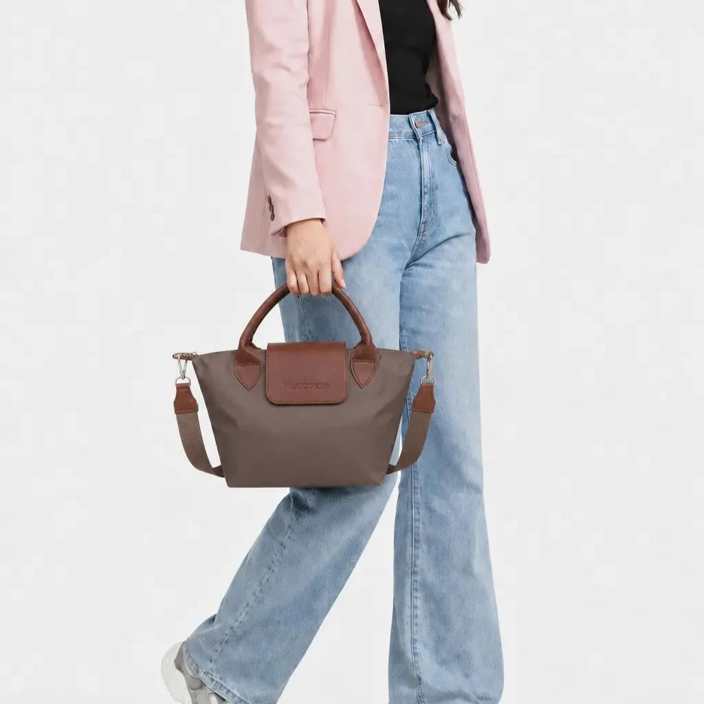 Person holding a brown handbag wearing a pink blazer and blue jeans on a white background
#color_choco brown