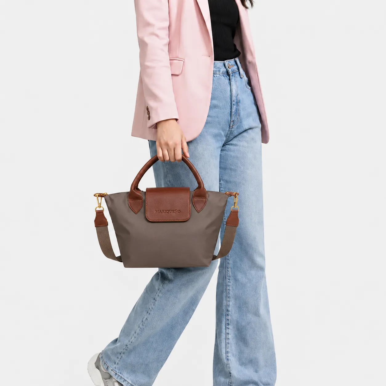 Person holding a brown handbag wearing a pink blazer and blue jeans on a white background
#color_choco brown