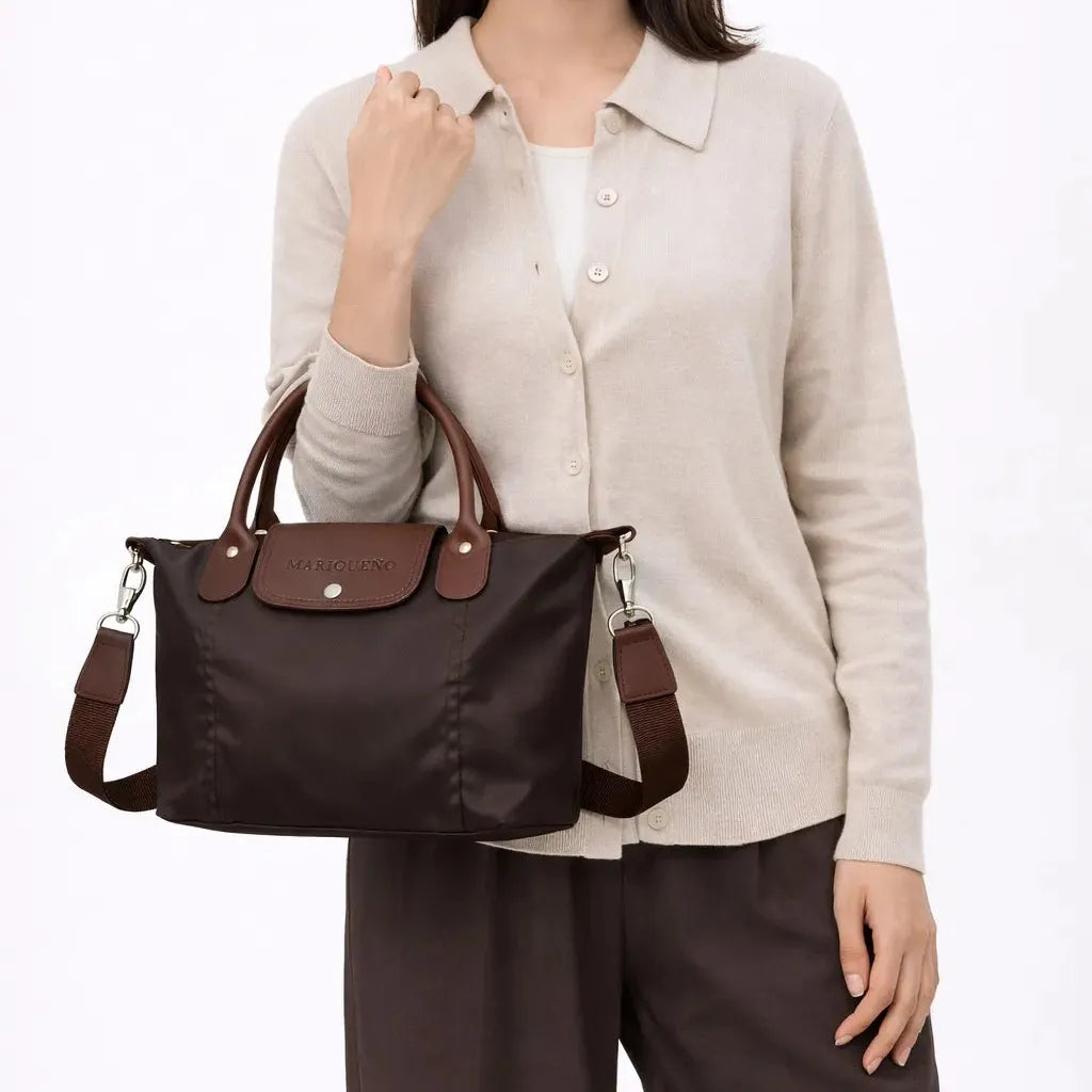 Person holding a brown handbag with visible brand logo against a white background
#color_choco brown