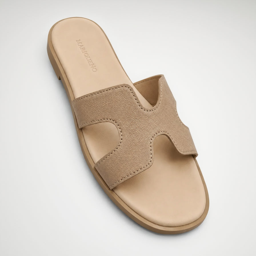 A single slide sandal by Mariqueno, shown from a top-down angle on a white background. The sandal features a wide, textured beige upper strap and a light beige footbed with the brand name 'MARIQUEÑO' printed on the insole.
#color_cream