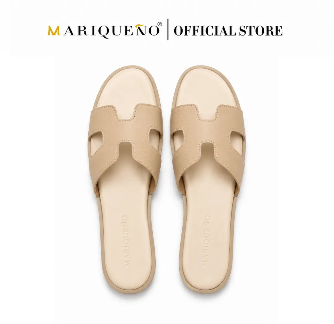 A pair of beige leather slide sandals with an H-shaped cutout strap, shown from a top-down view on a white background with 'MARIQUEÑO | OFFICIAL STORE' text at the top.
#color_cream