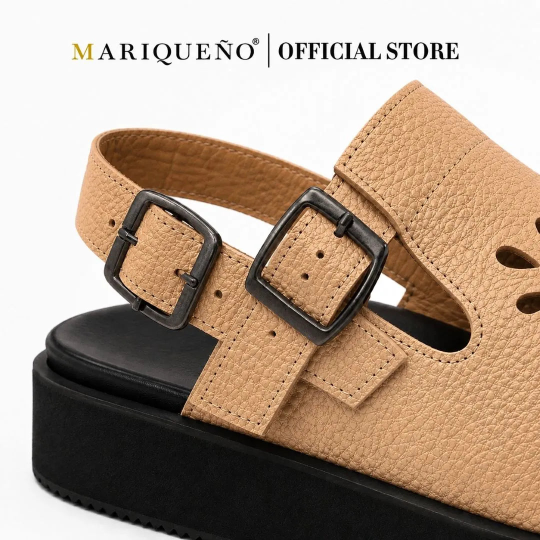 A close-up of a tan pebbled leather mule sandal with two black buckle straps and a chunky black platform sole, shown on a white background with the text 'MARIQUENO | OFFICIAL STORE' at the top.
#color_beige