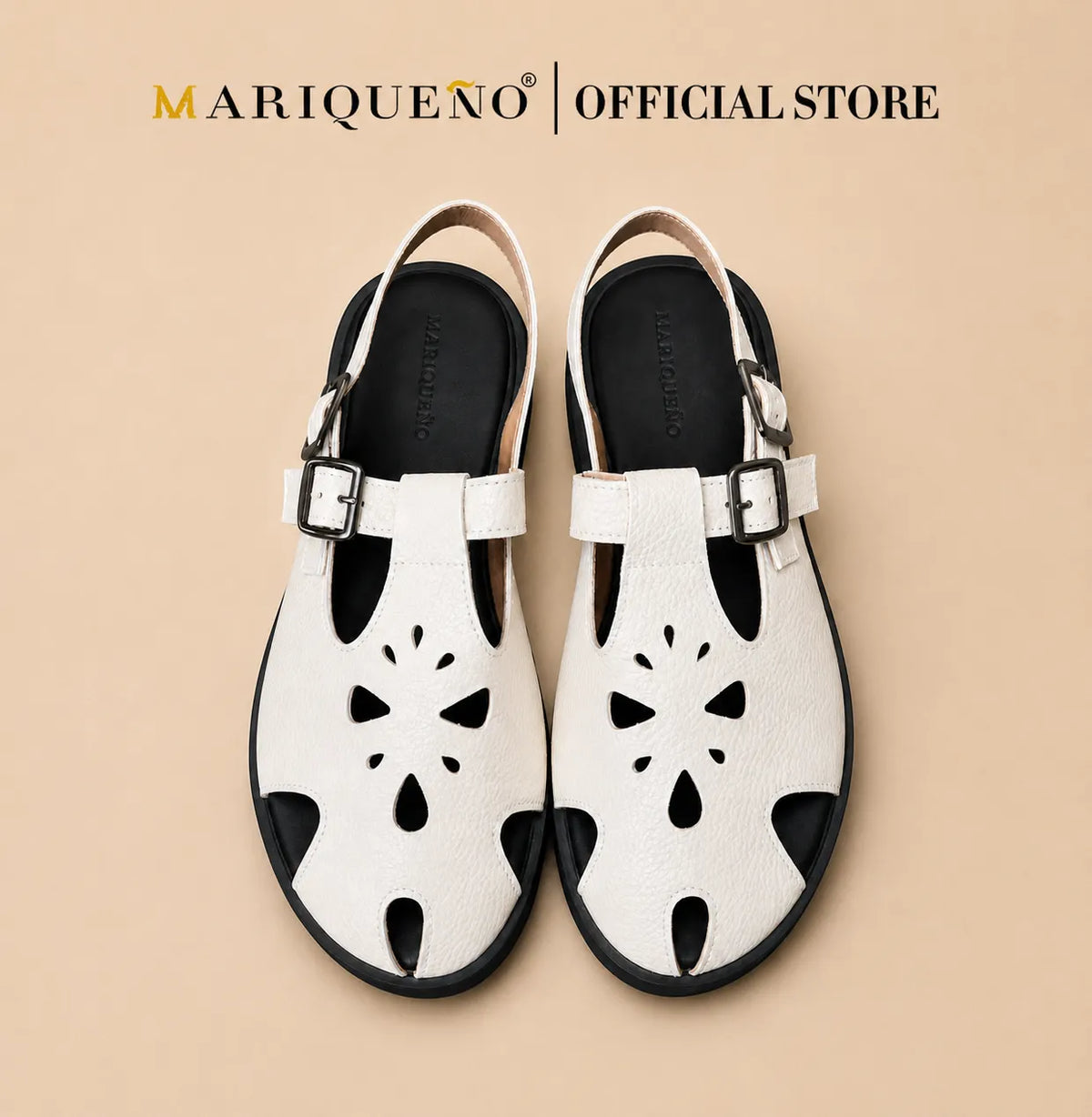 A pair of white leather clog sandals with black cutout floral details on the front, black soles, and silver buckle straps, shown from a top-down view on a white background with 'MARIQUENO | OFFICIAL STORE' text at the top.
#color_white