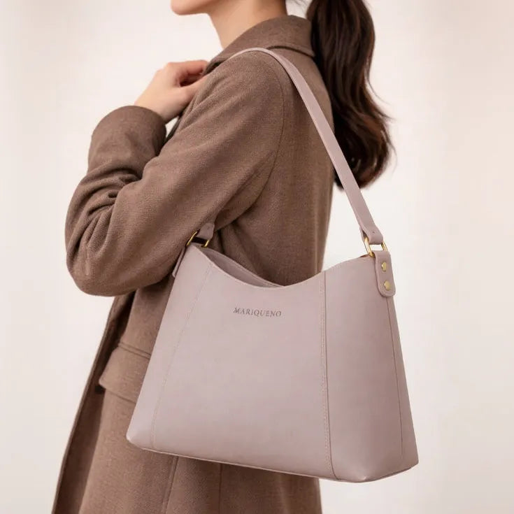 Person wearing a taupe handbag with 'Mariqueno' branding on a plain background
#color_taupe