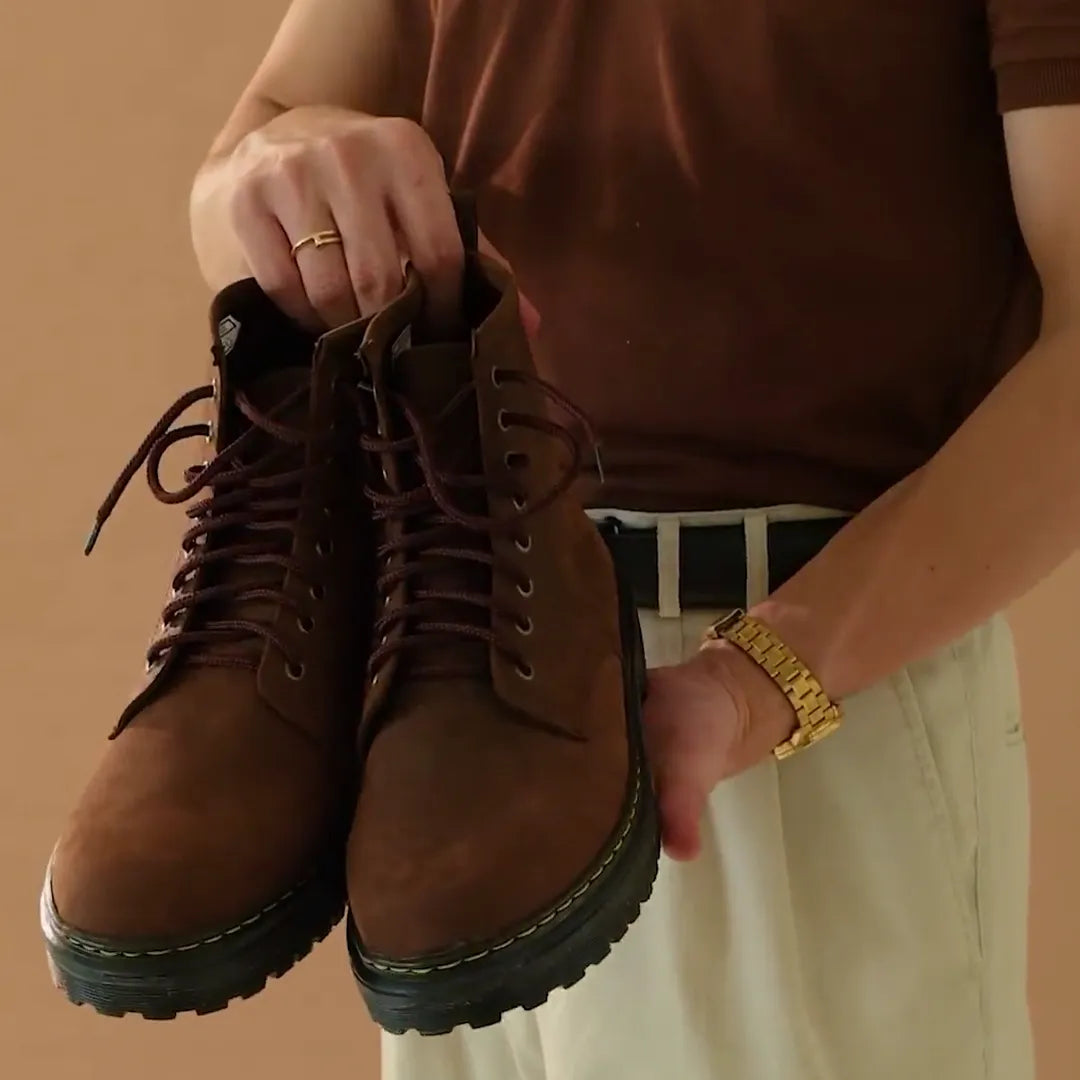 Man holding a pair of brown matted high cut boots
#color_malt brown