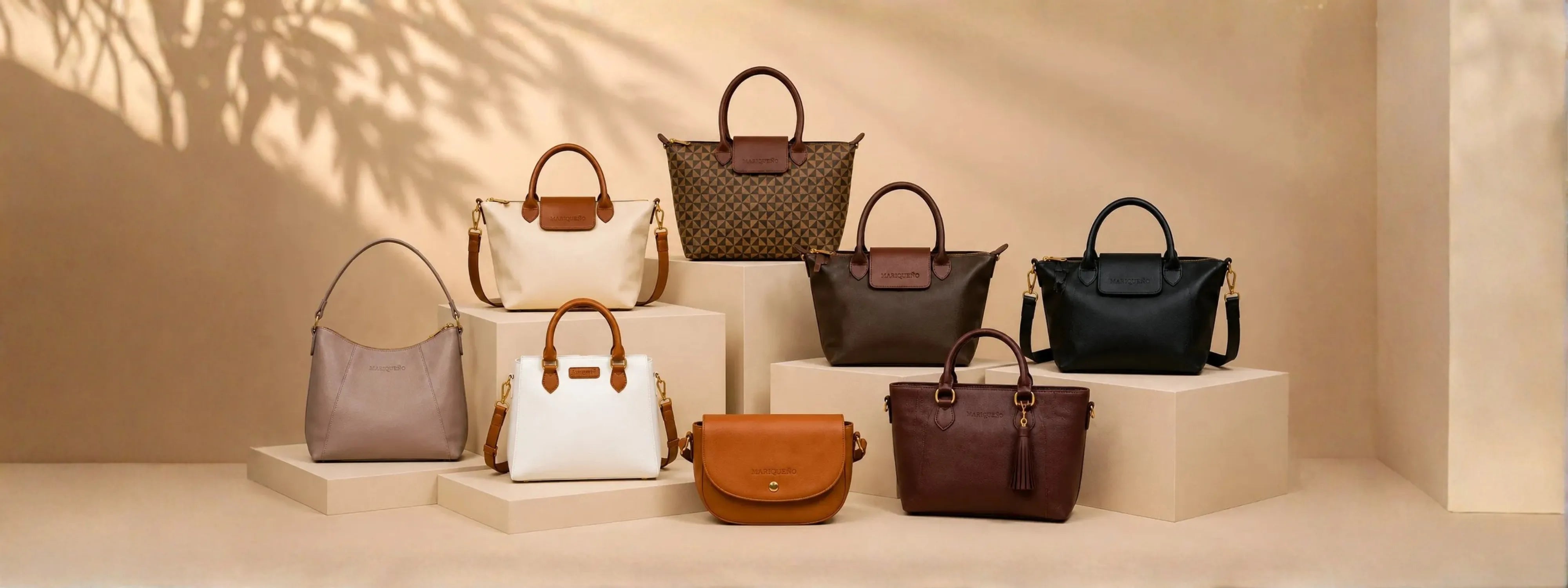 A collection of eight handbags in various colors and styles, arranged on beige pedestals against a warm beige background with soft leaf shadows.