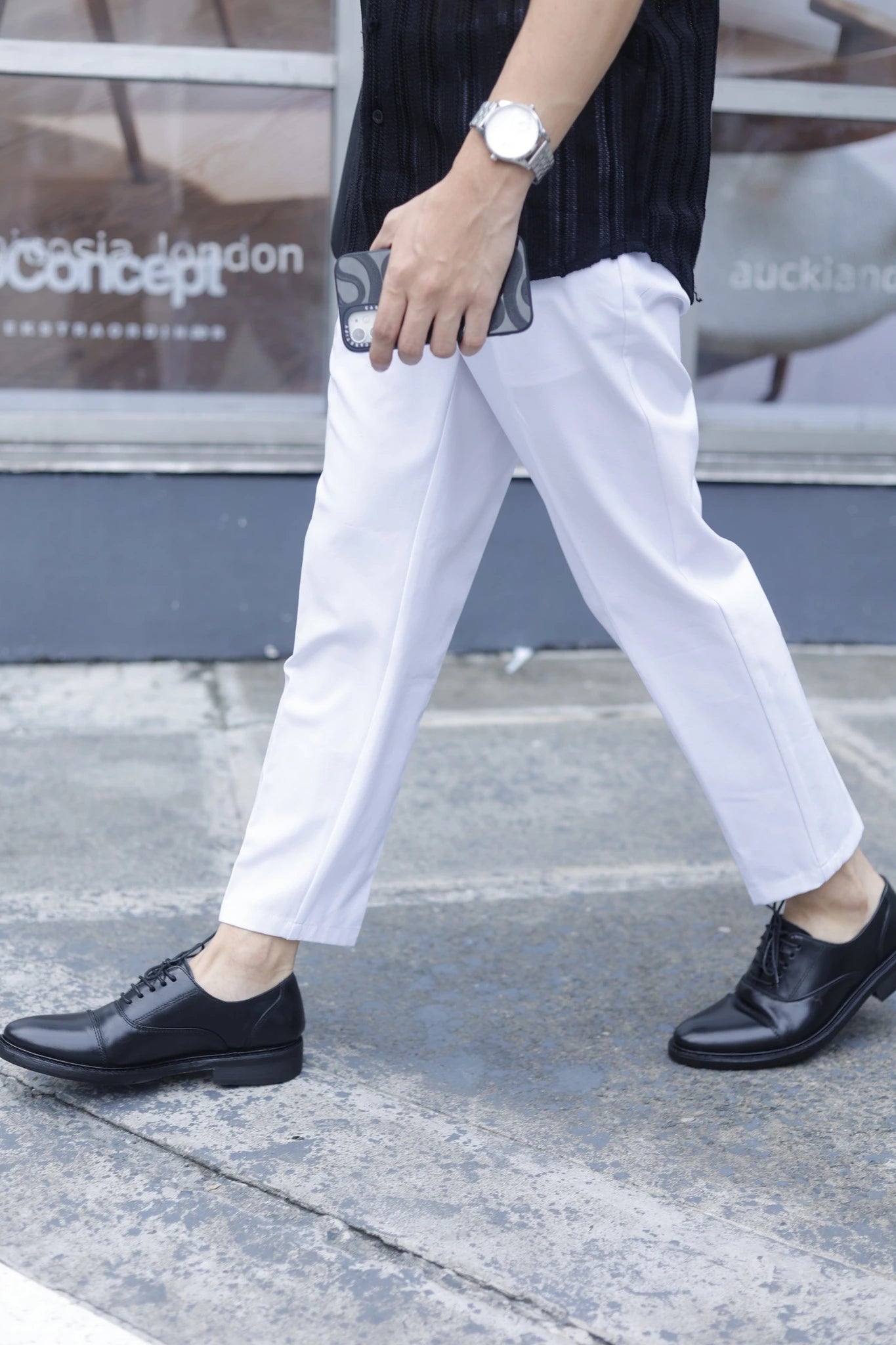 Person wearing white pants and black shoes on a sidewalk with a blurred background
#color_black