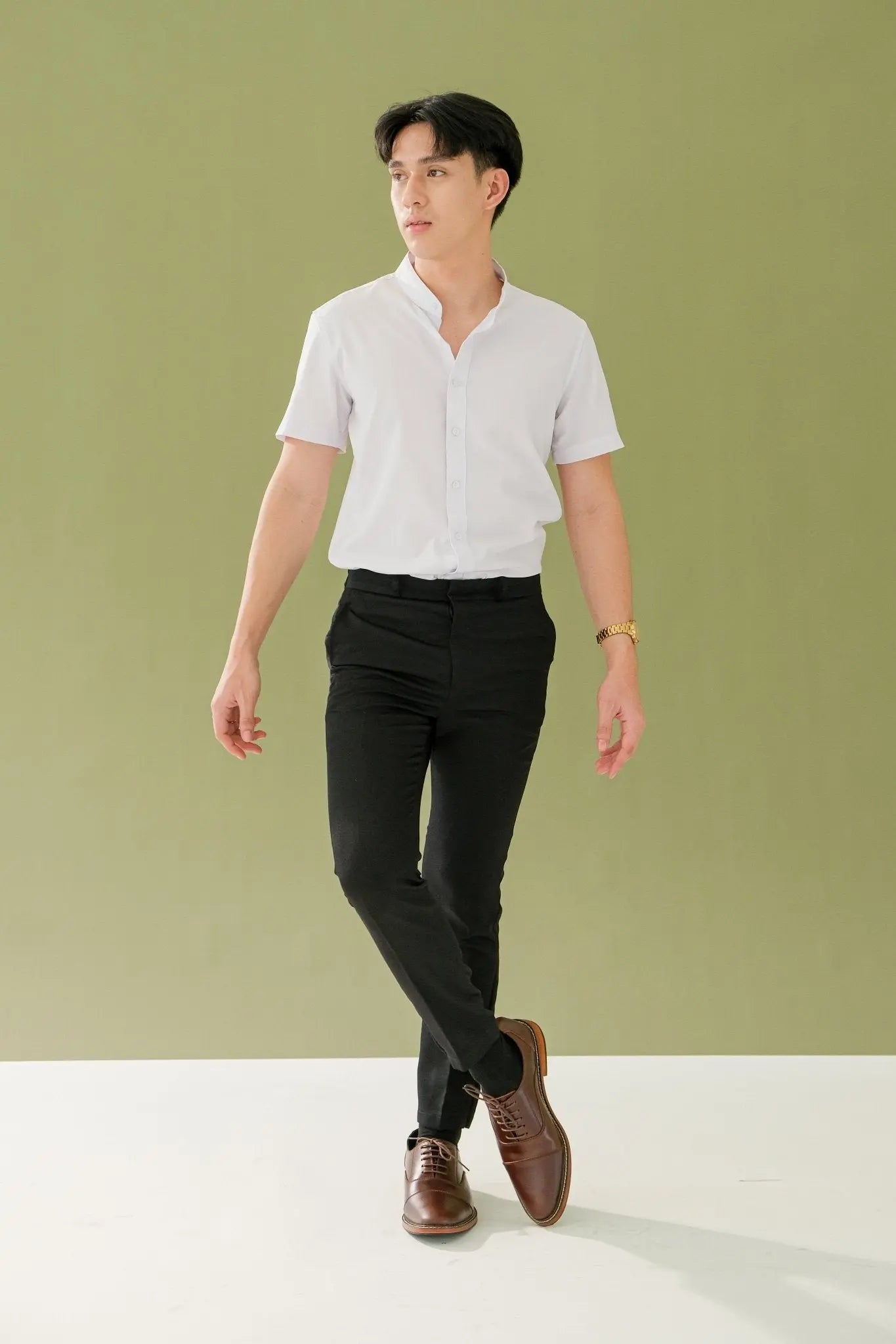 Man wearing a white shirt, black pants, and brown shoes against a green background
#color_walnut