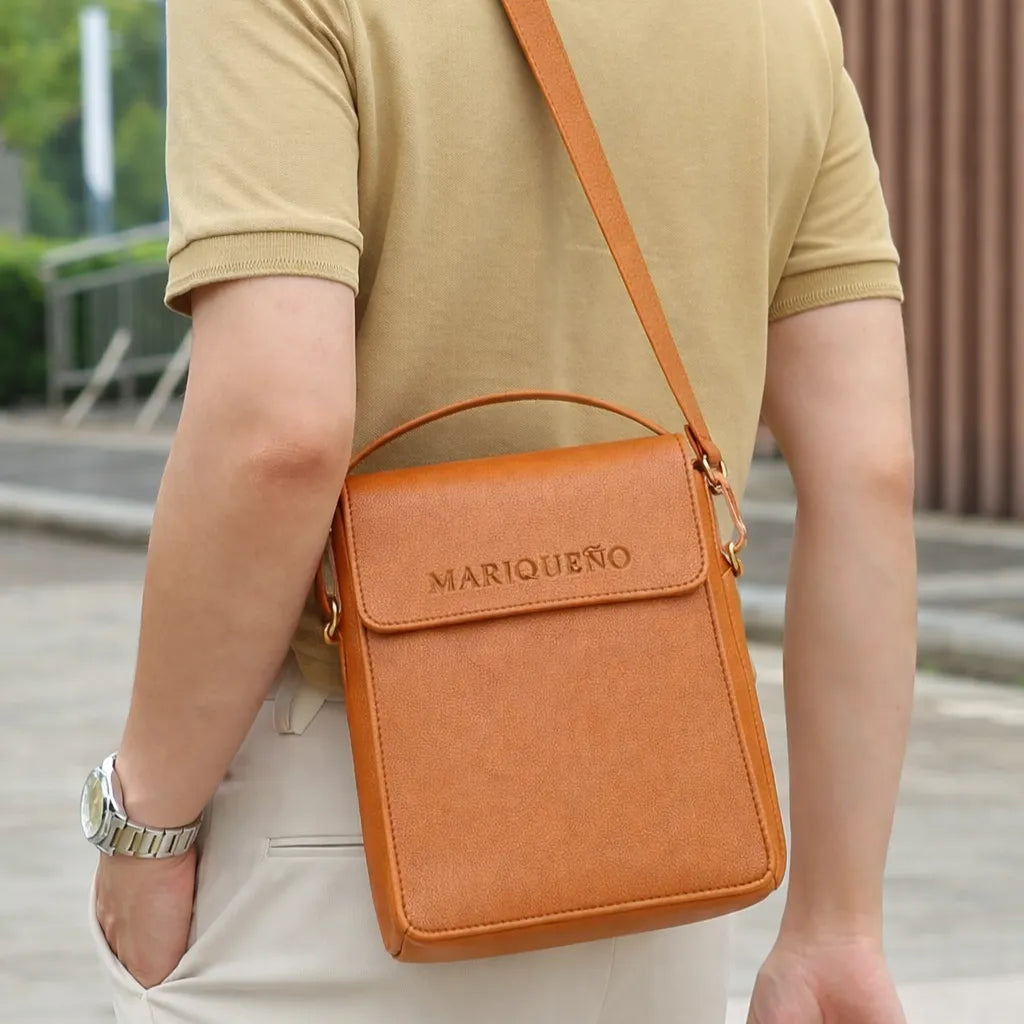 Person wearing a tan brown leather crossbody bag with 'MARIQUENO' branding.
#color_tan