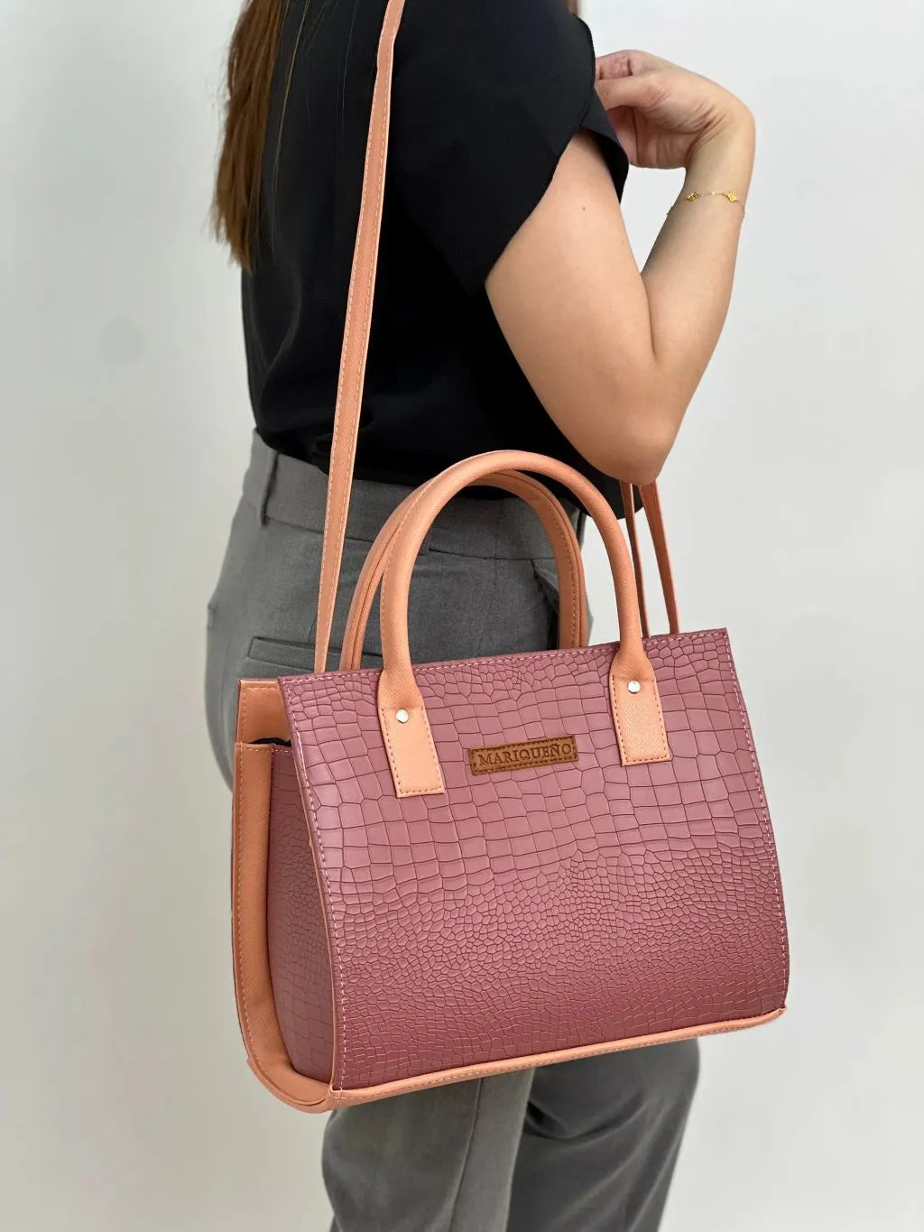 Person holding a pink handbag with brown accents against a plain background
#color_old rose
