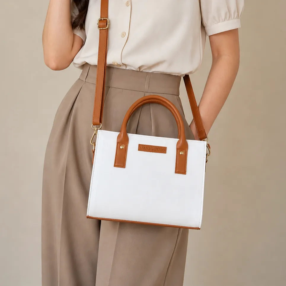 Person holding a white handbag with brown handles and strap against a beige background
#color_off white