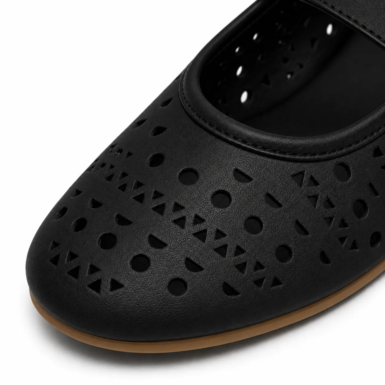 A close-up of a black perforated shoe with geometric cutouts and a tan outsole, shown on a white background.
#color_black