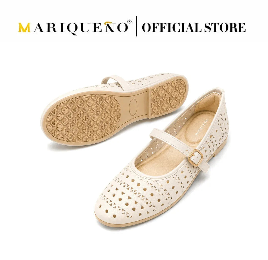 A pair of off-white Mary Jane flat shoes with circular cutouts, featuring a gold-tone buckle and a tan outsole, shown against a white background with 'MARIQUENO | OFFICIAL STORE' text at the top.
#color_white