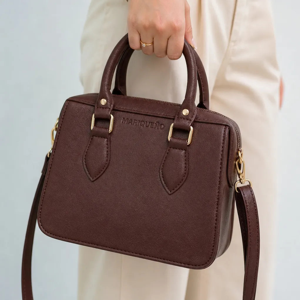 Woman in a white dress holding a brown handbag against a beige background
#color_choco brown