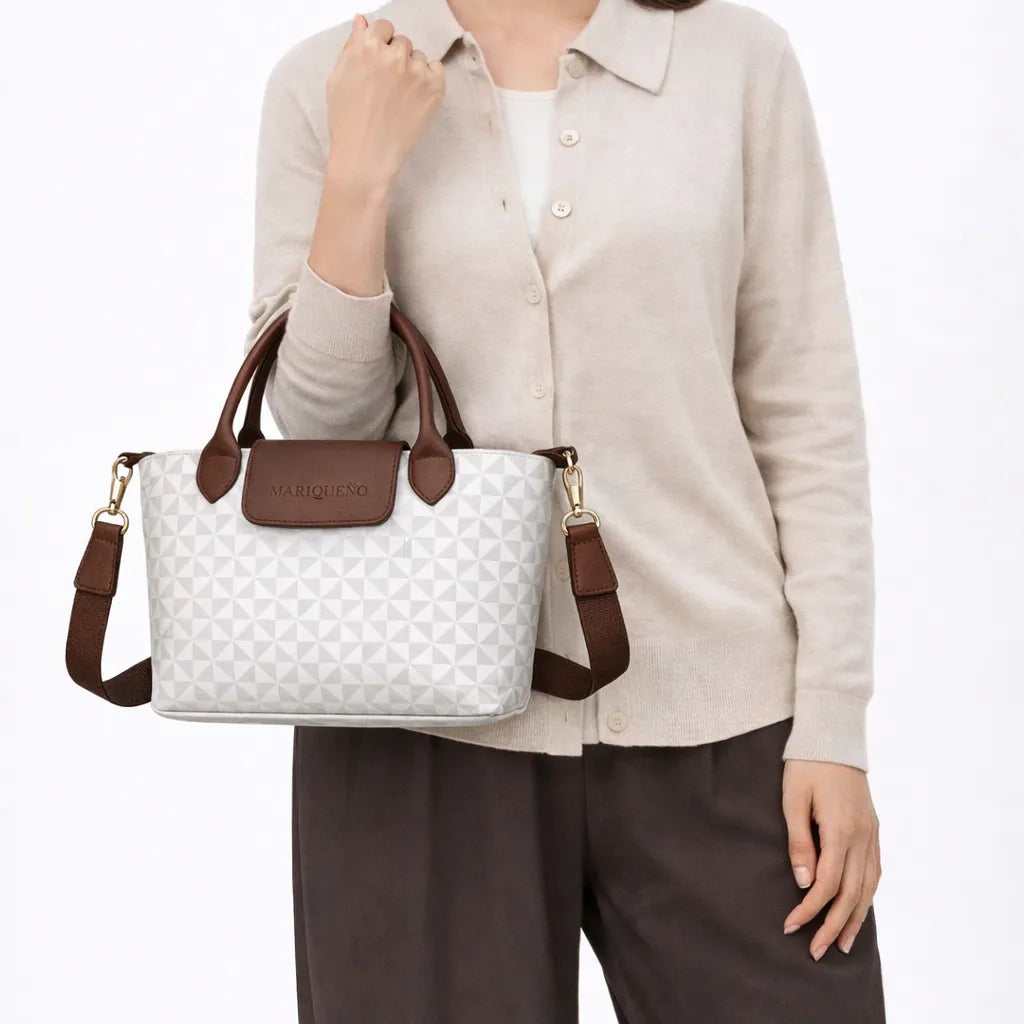 Person holding a white geo patterned handbag with brown straps and accents, wearing a beige shirt and brown pants.
#color_sandstone geo
