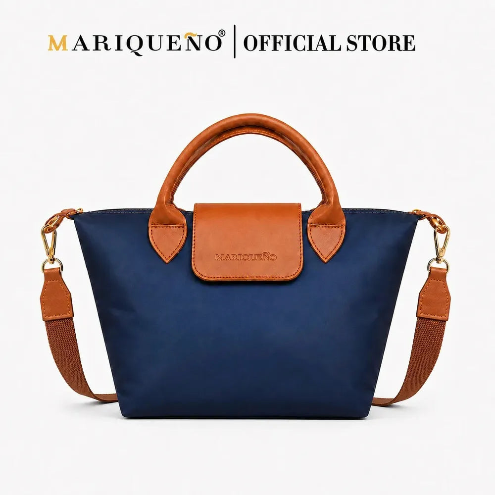 A navy blue nylon tote bag with tan leather handles, trim, and a matching front flap, shown on a clean white background. The Mariqueno brand name is displayed at the top of the image.
#color_navy blue