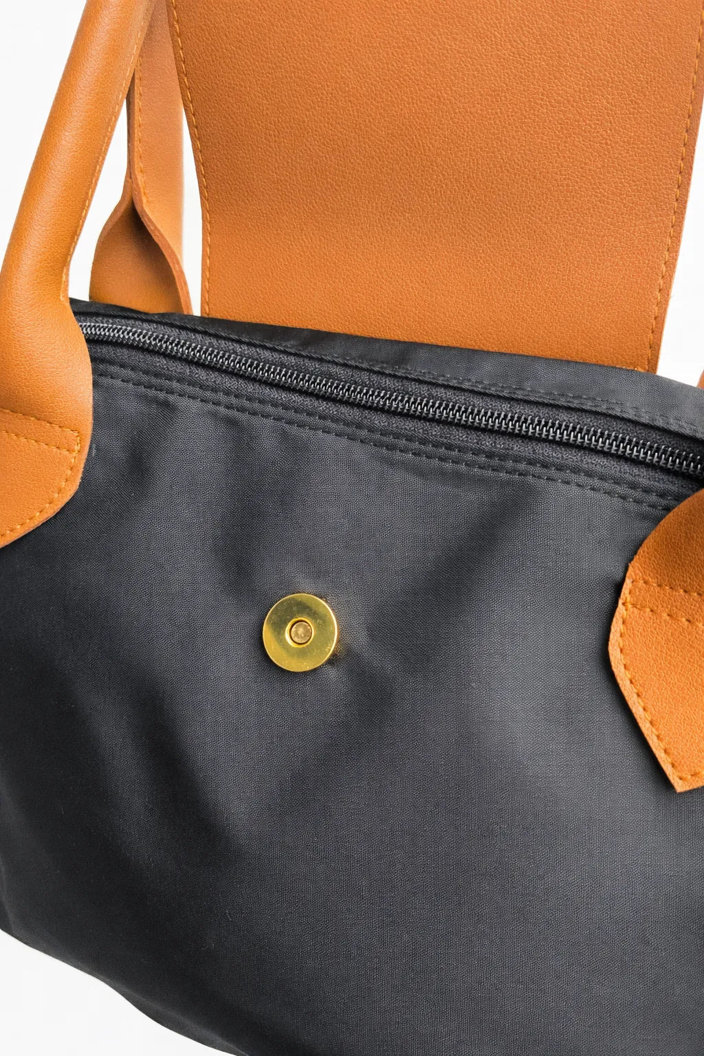 Close-up of a black bag with orange handles and trim, featuring a gold button.
#color_black
