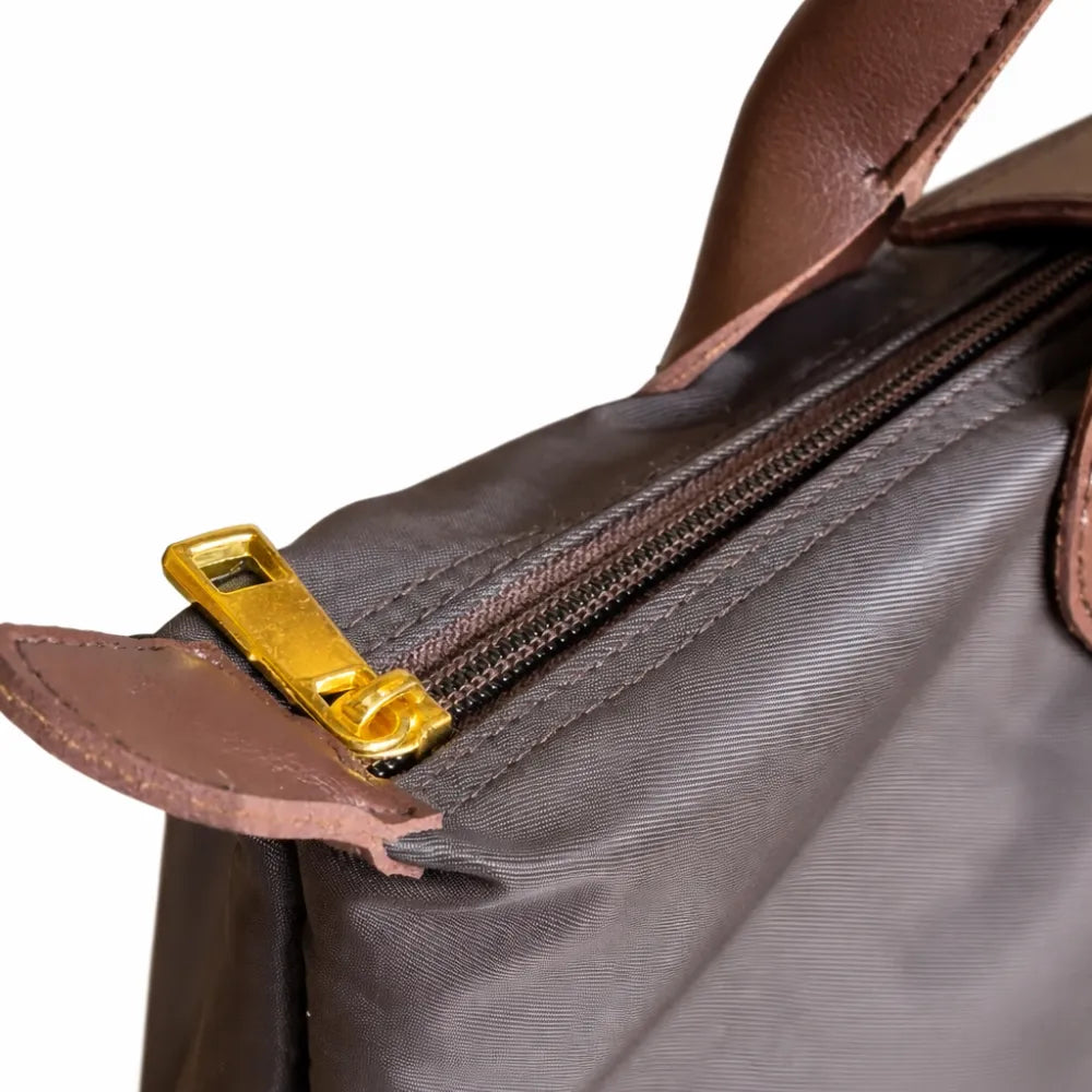 Close-up of a brown leather bag with a gold zipper pull on a white background
#color_choco brown