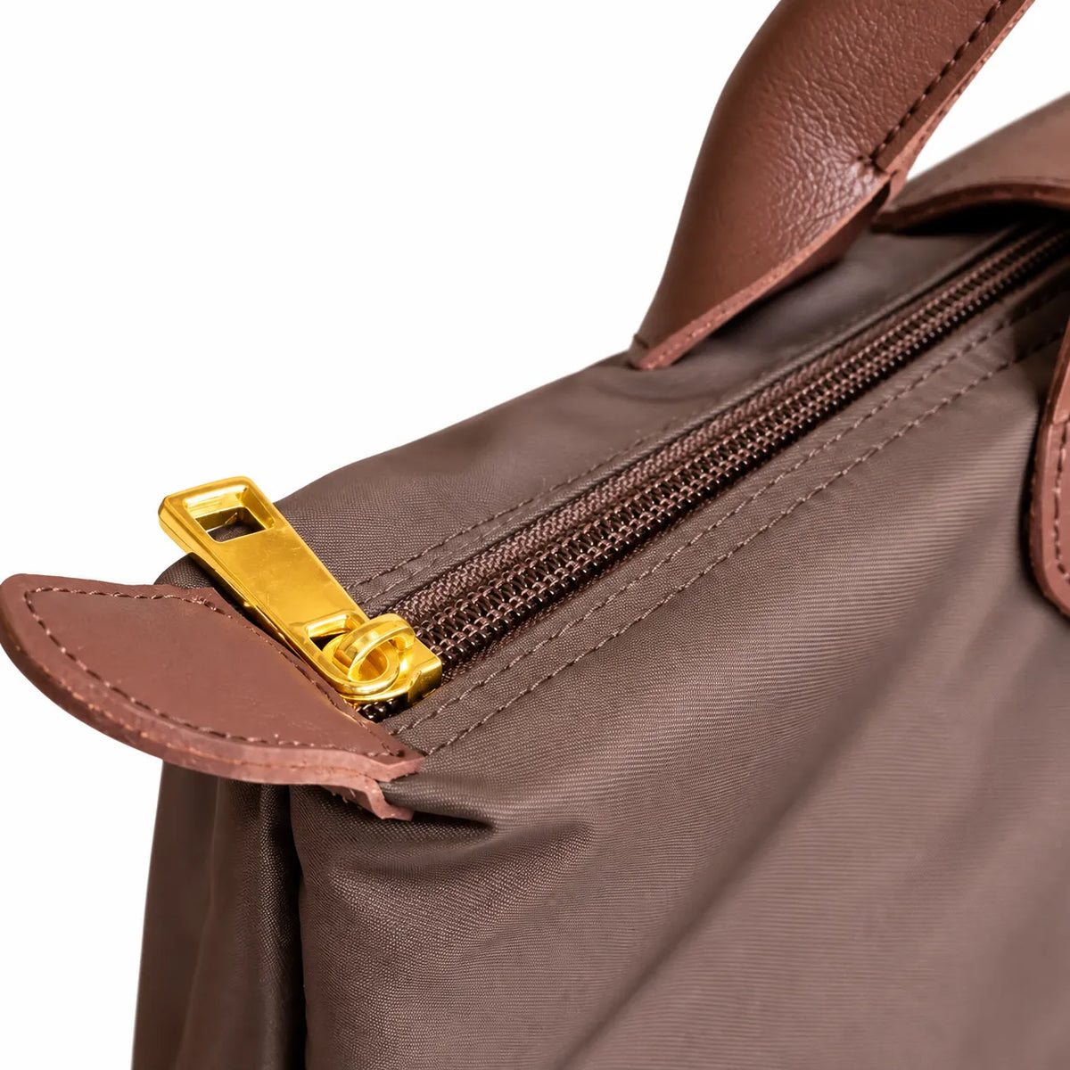 Close-up of a brown leather bag with a gold zipper pull on a white background
#color_choco brown