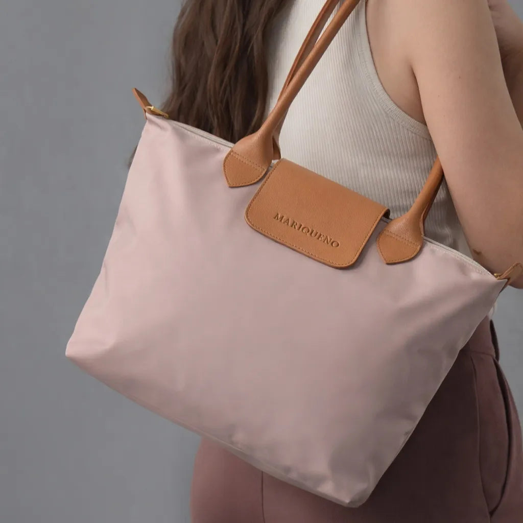 Taupe tote bag with brown leather accents held by a person against a gray background
#color_taupe