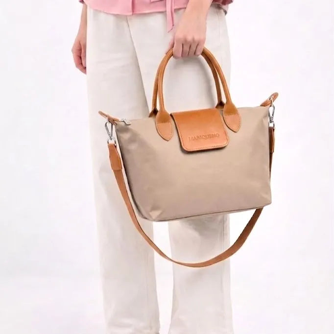 Beige handbag with brown handles and strap held by a person on a white background
#color_taupe