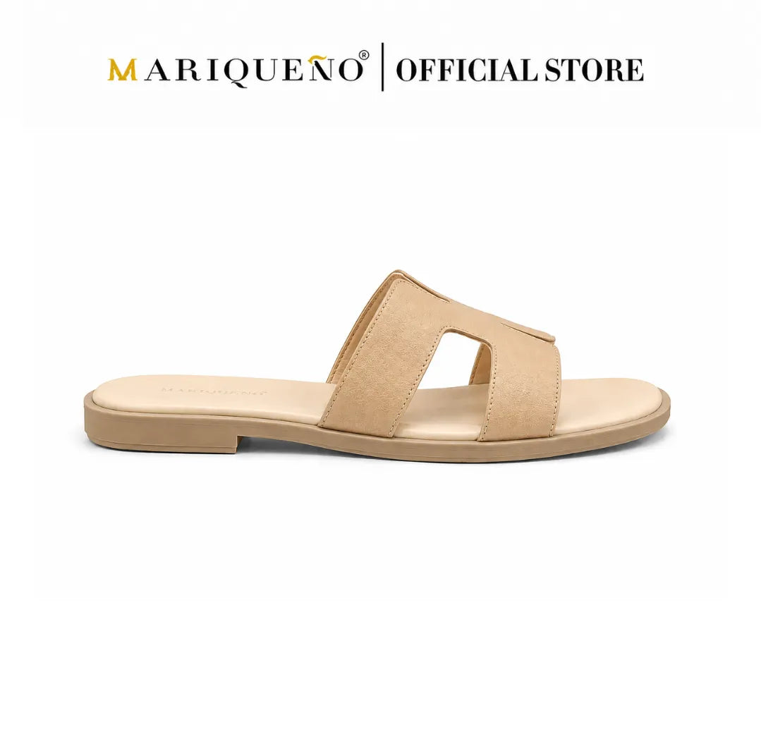 A single flat slide sandal in a light tan/beige color, shown from a side profile on a white background with the text 'MARIQUEÑO | OFFICIAL STORE' at the top.
#color_cream