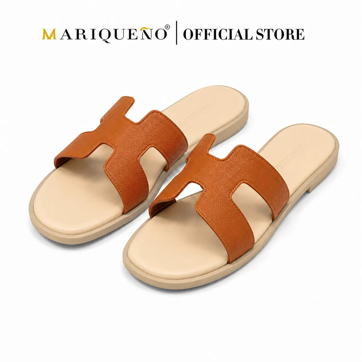 A pair of women's slide sandals with a textured brown leather strap in an H-shape over a beige footbed and sole, shown on a white background with 'MARIQUEÑO | OFFICIAL STORE' text at the top.
#color_tan
