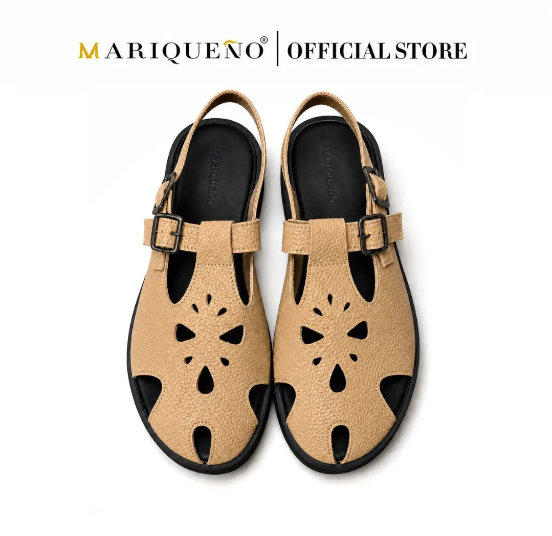 A pair of tan leather slide sandals with floral cutouts and adjustable buckle straps, shown from a top-down view on a white background with 'MARIQUENO | OFFICIAL STORE' text at the top.
#color_beige
