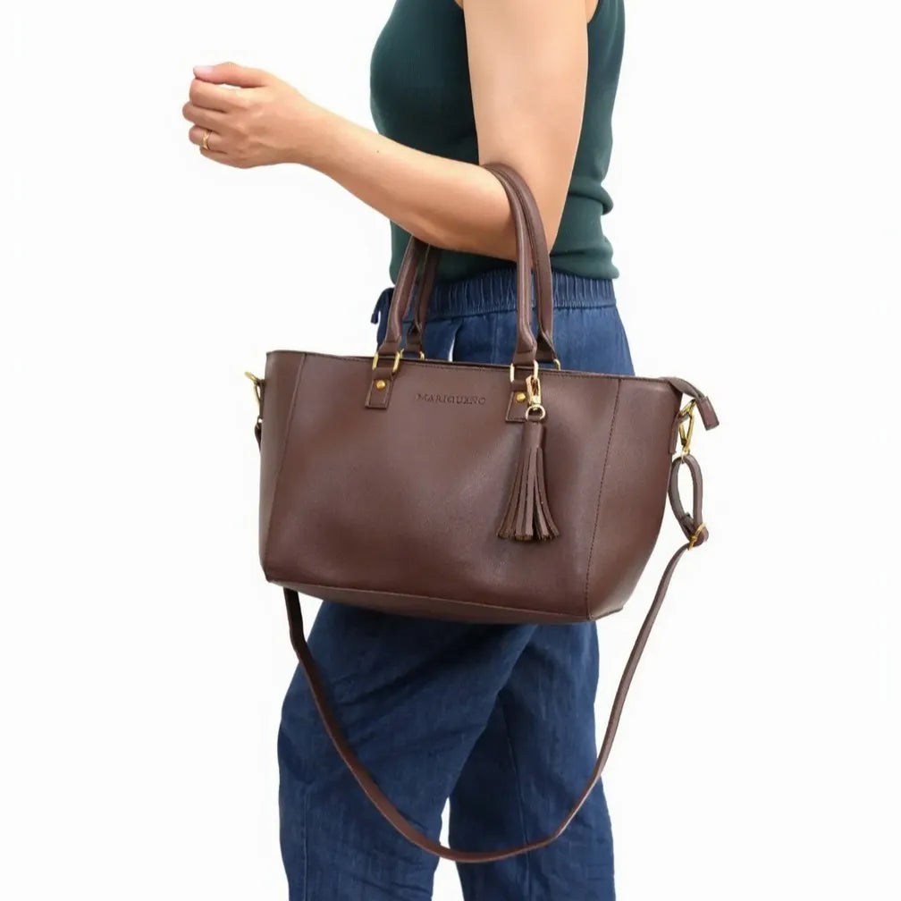 Brown handbag with a brand logo held by a person wearing blue jeans on a white background
#color_choco brown