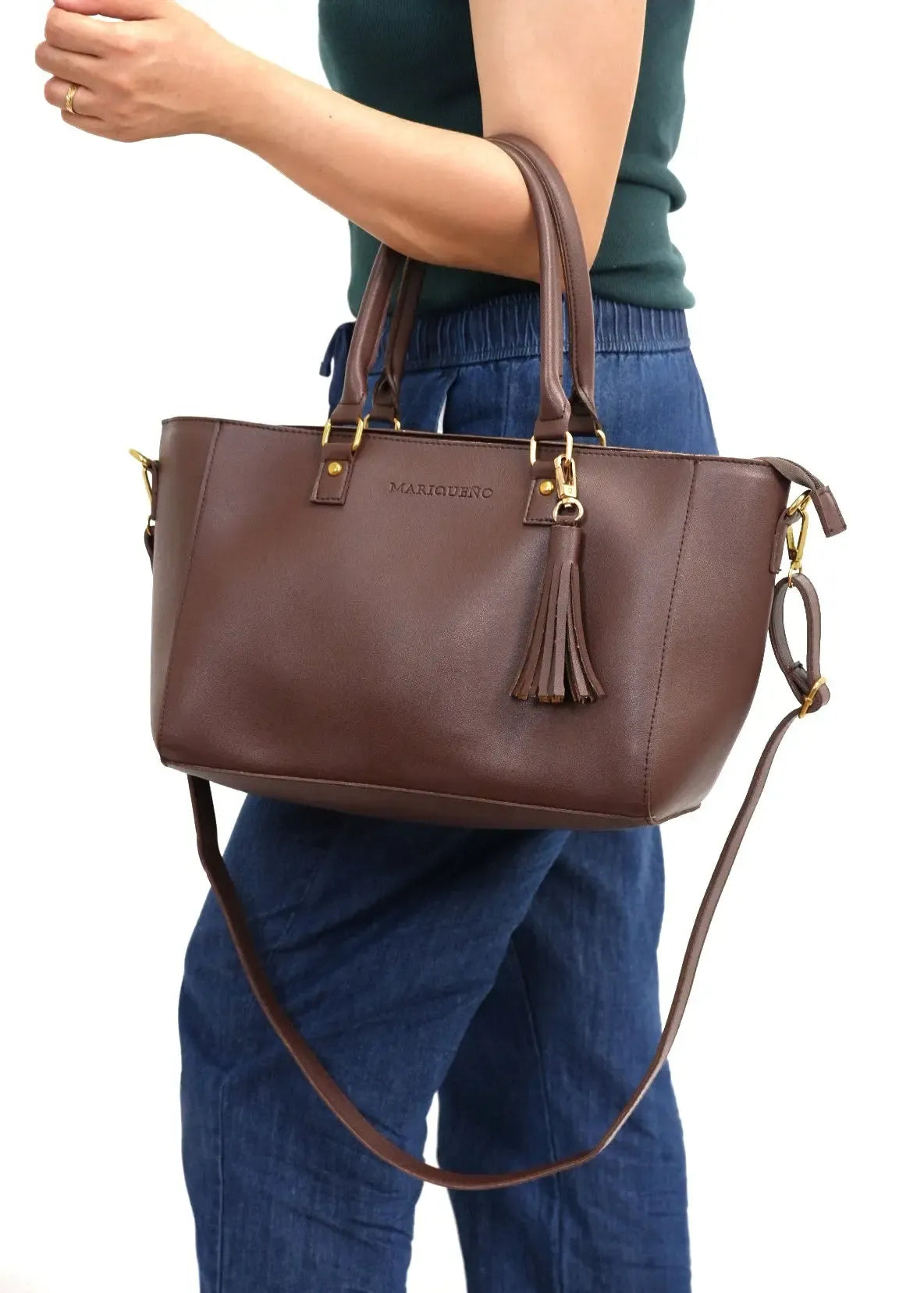 Brown handbag with a brand logo held by a person wearing blue jeans on a white background
#color_choco brown