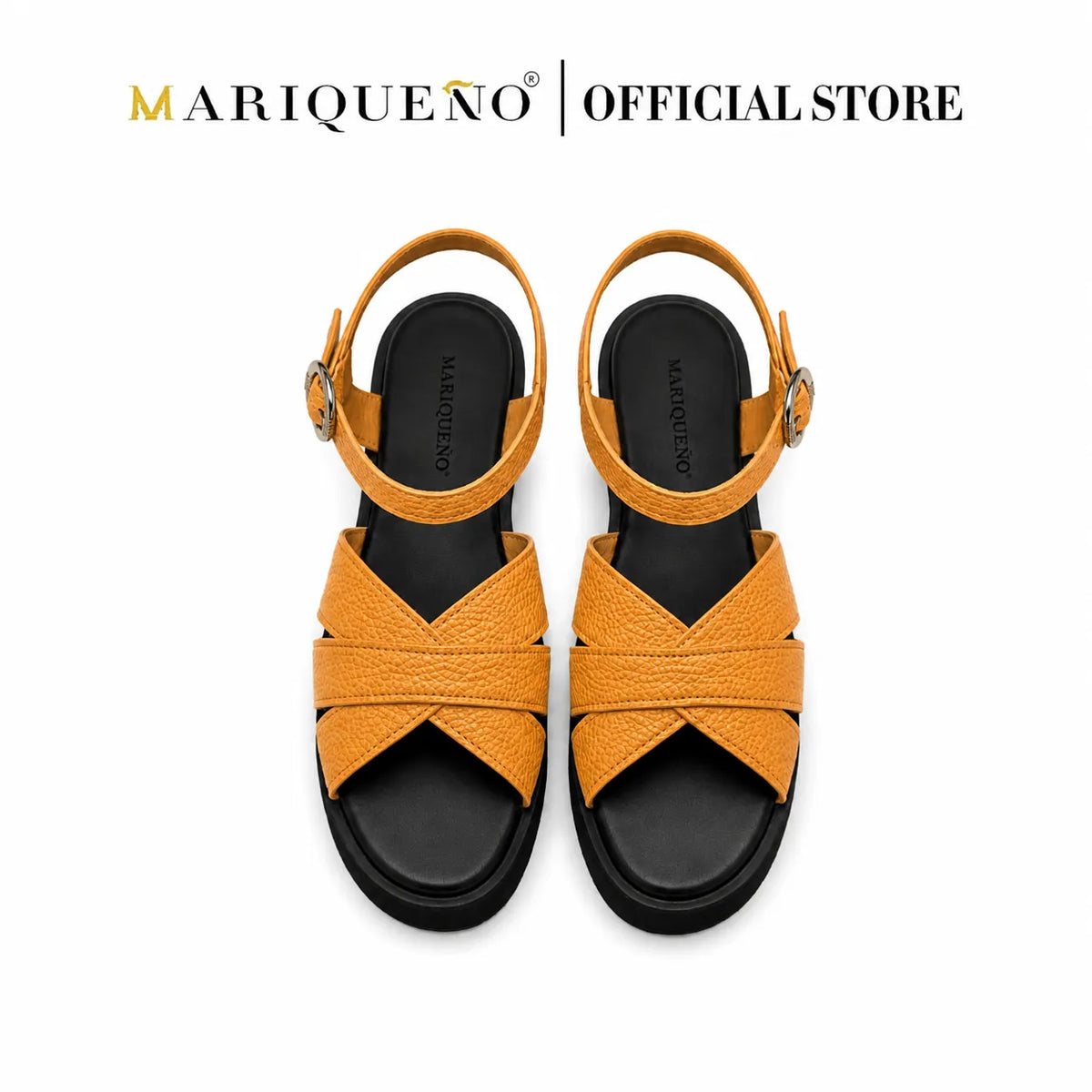 A pair of Mariqueno women's flat sandals in tan leather with a black sole and adjustable ankle straps, shown from a top-down view on a white background with the 'MARIQUEÑO | OFFICIAL STORE' logo at the top.
#color_tan