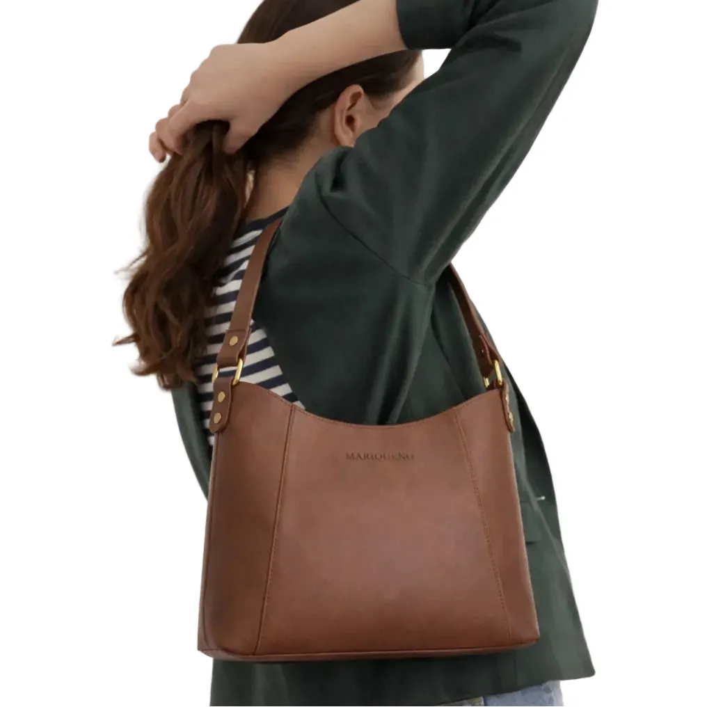 Person wearing a brown leather handbag with 'Mariqueno' branding on a plain background
#color_choco brown