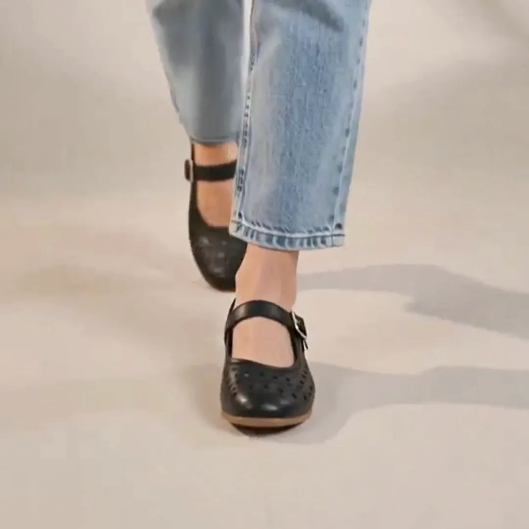 Close up of black flat shoes worn by a woman.
#color_black